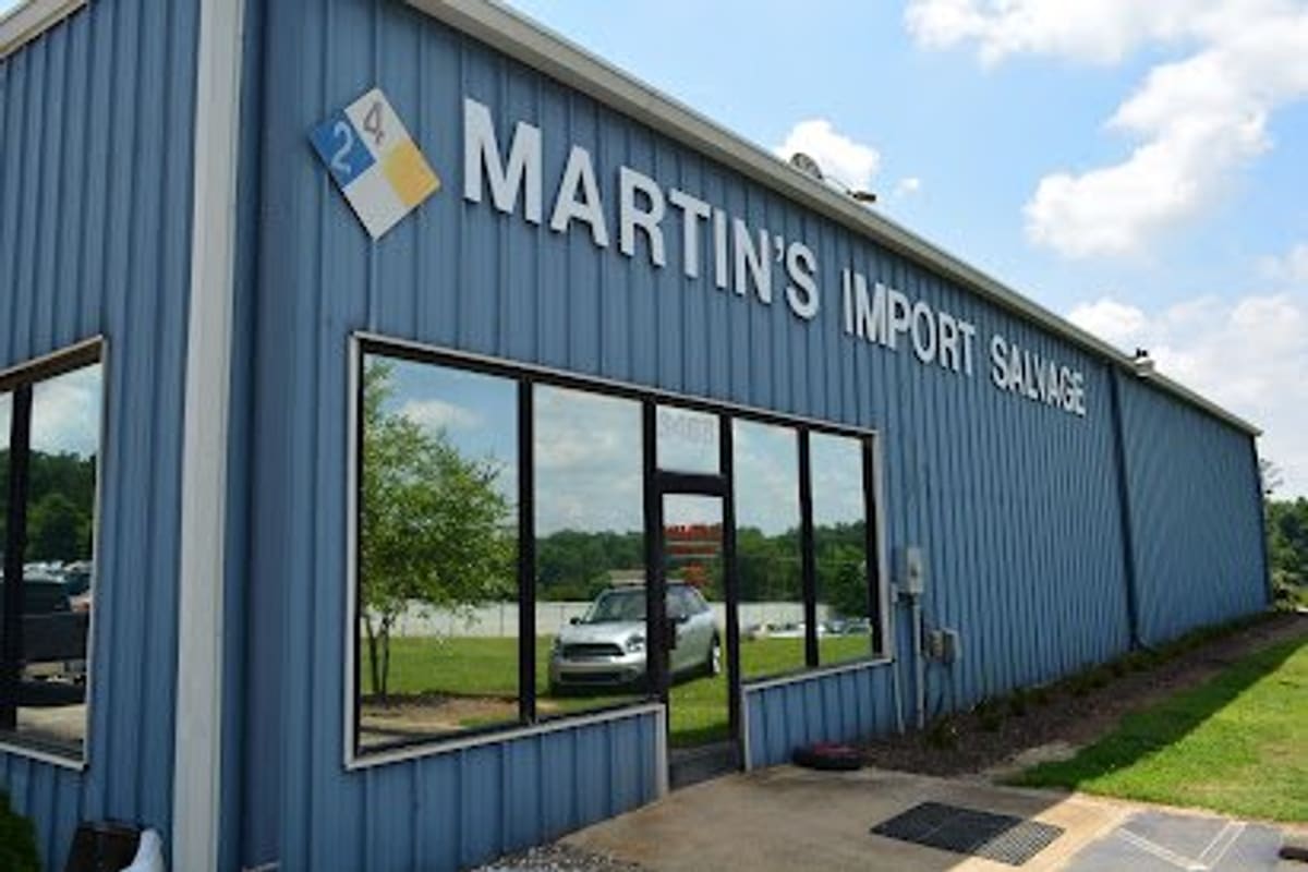 Martin's Import Salvage: Blue metal office building with large front windows and a sign reading Martin's Import Salvage, beside a grassy lawn