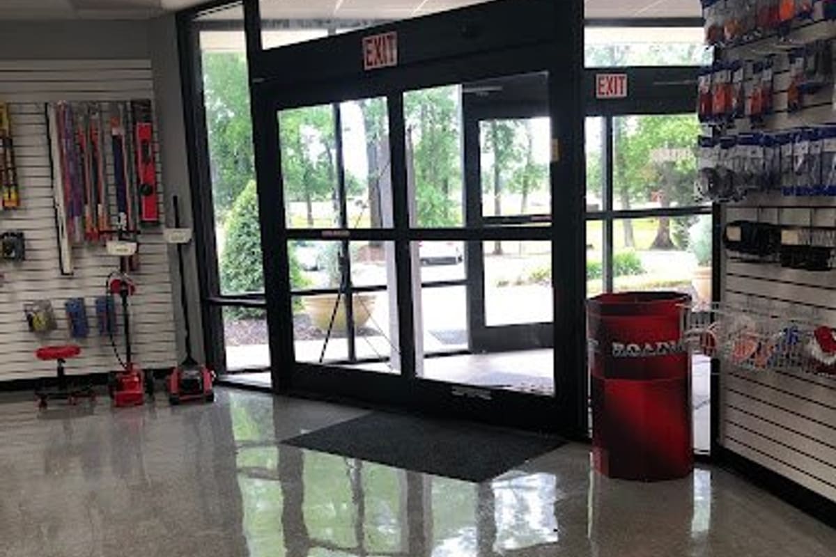 Stone Truck Parts: Interior view of glass entrance doors with exit signs, shiny floor, and slatwall displays of auto accessories on both sides