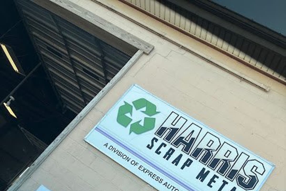 Harris Auto Recycling: Two Harris Scrap Metal signs with recycling symbols on a tan building wall beside a handicap parking sign