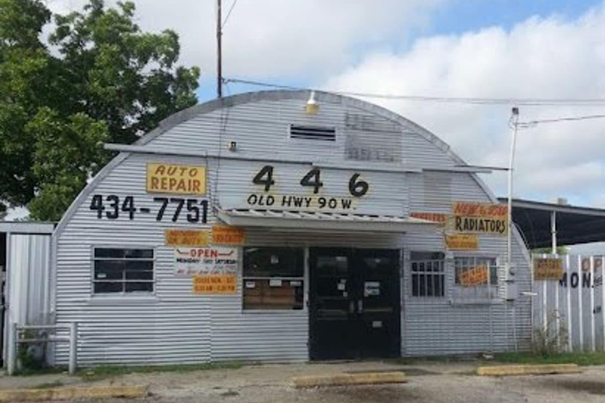 Alamo Access Used Auto Parts: Corrugated metal quonset-style shop building with auto repair and radiator signs, street number 446 and a paved lot in front