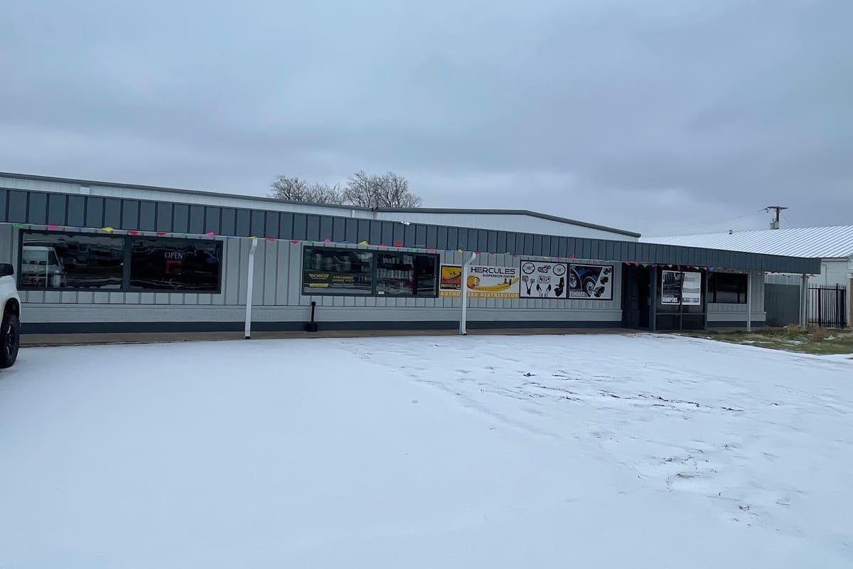 AFG Truck Parts: Single-story gray metal commercial building with storefront windows and banners, seen from a snow-covered parking lot