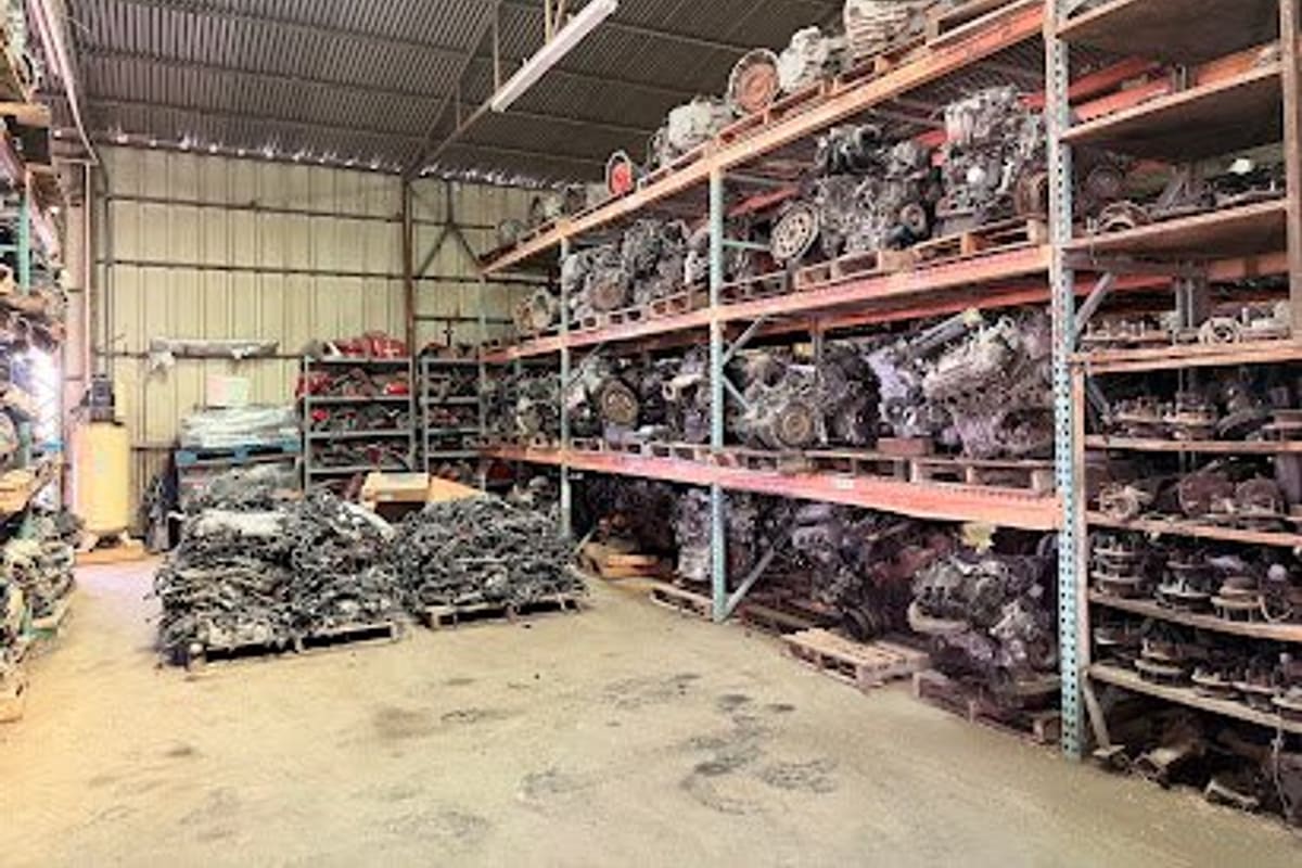 Hwy 6 Auto Recycling: Inside a covered warehouse with tall shelving racks full of used engines and transmissions and pallets of parts on the floor