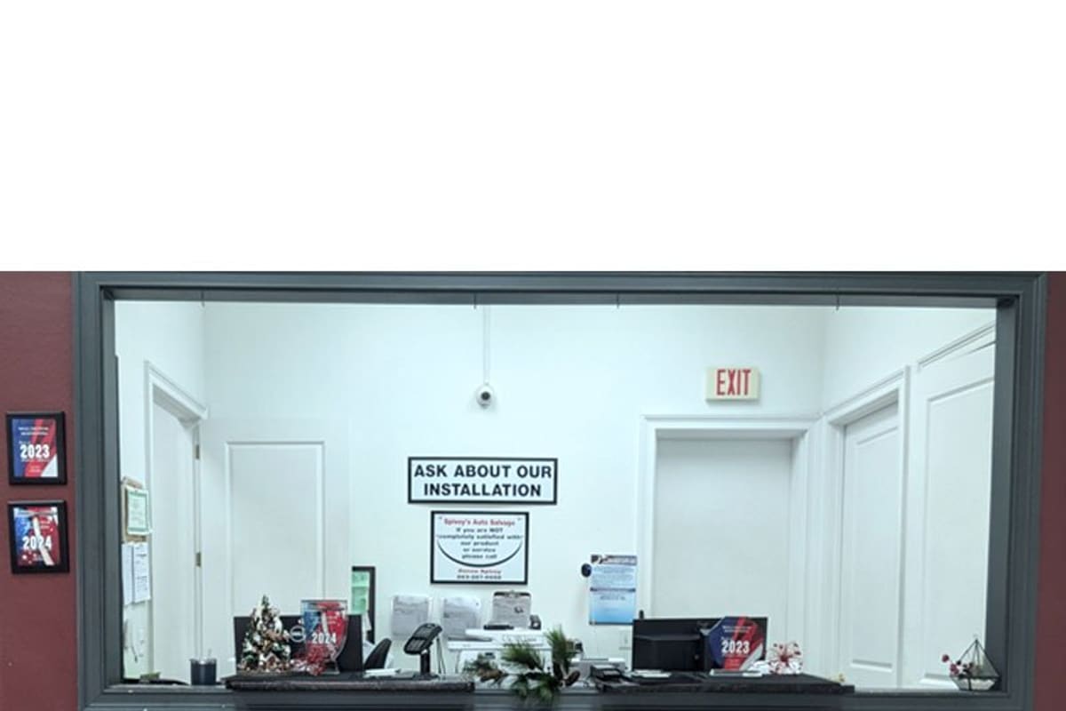 Spivey's Auto Salvage: Customer service counter window inside the office with awards on the wall and a receipt required sign below