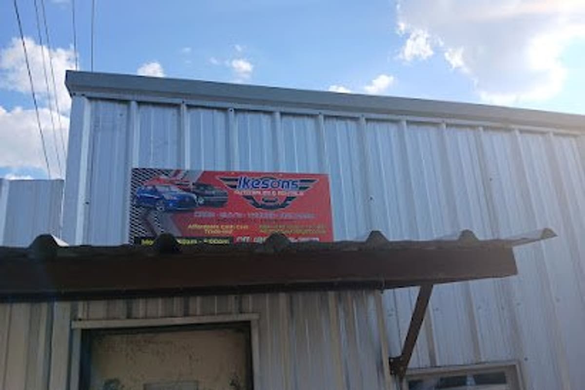 Ikesons Auto Parts: Red auto parts sign mounted on a corrugated metal building above a rusty awning and a door