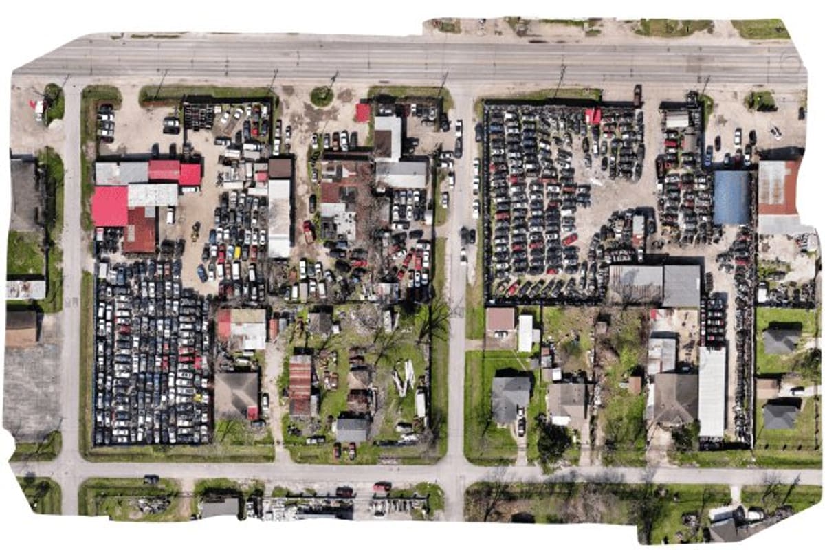 L & E Auto Parts: Aerial view of a salvage yard with dense rows of vehicles, several buildings and surrounding streets in daylight