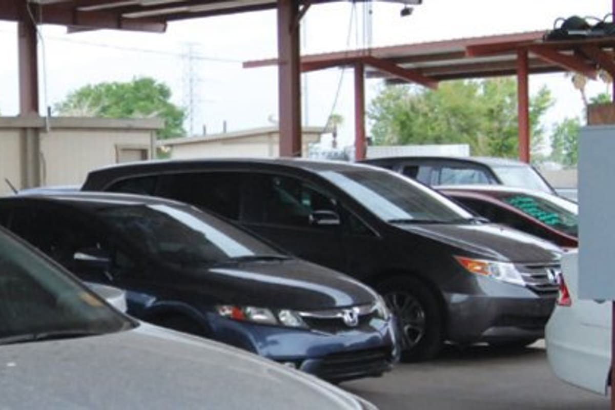 JLJ Auto Recovery: Cars parked in rows under covered metal carports at a vehicle storage lot