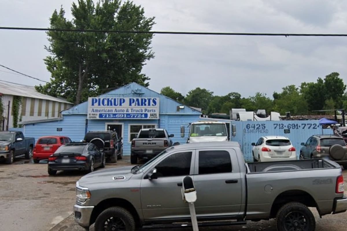 Pickup Parts: Blue building with a pickup parts sign beside a gravel lot filled with trucks, SUVs and salvage vehicles
