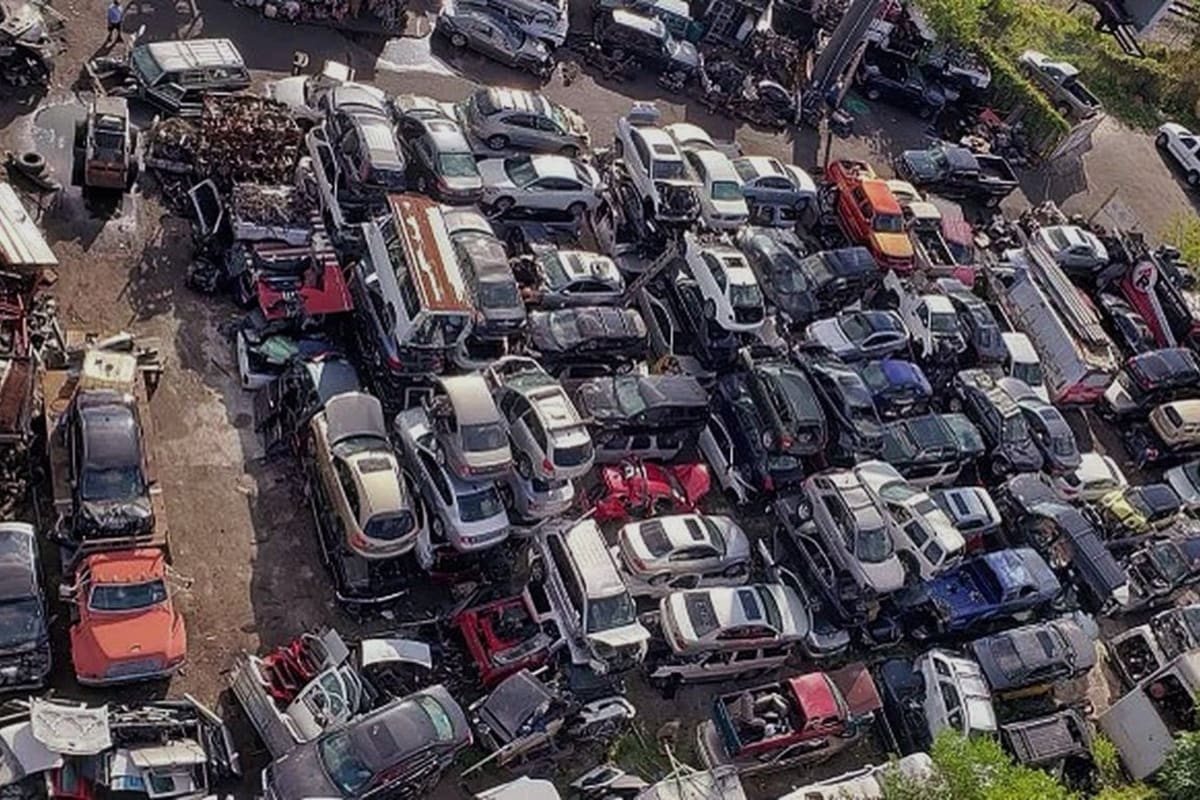 733 Parts: Aerial view of a crowded salvage yard with rows of stacked and parked cars next to a railway line