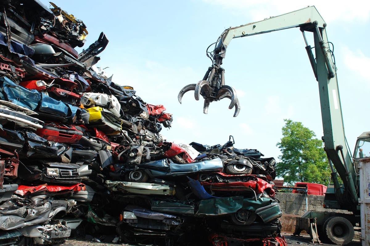 Apache Iron Metal & Auto Salvage: Large stacks of crushed cars in a salvage yard with a material handler crane and grapple lifting scrap