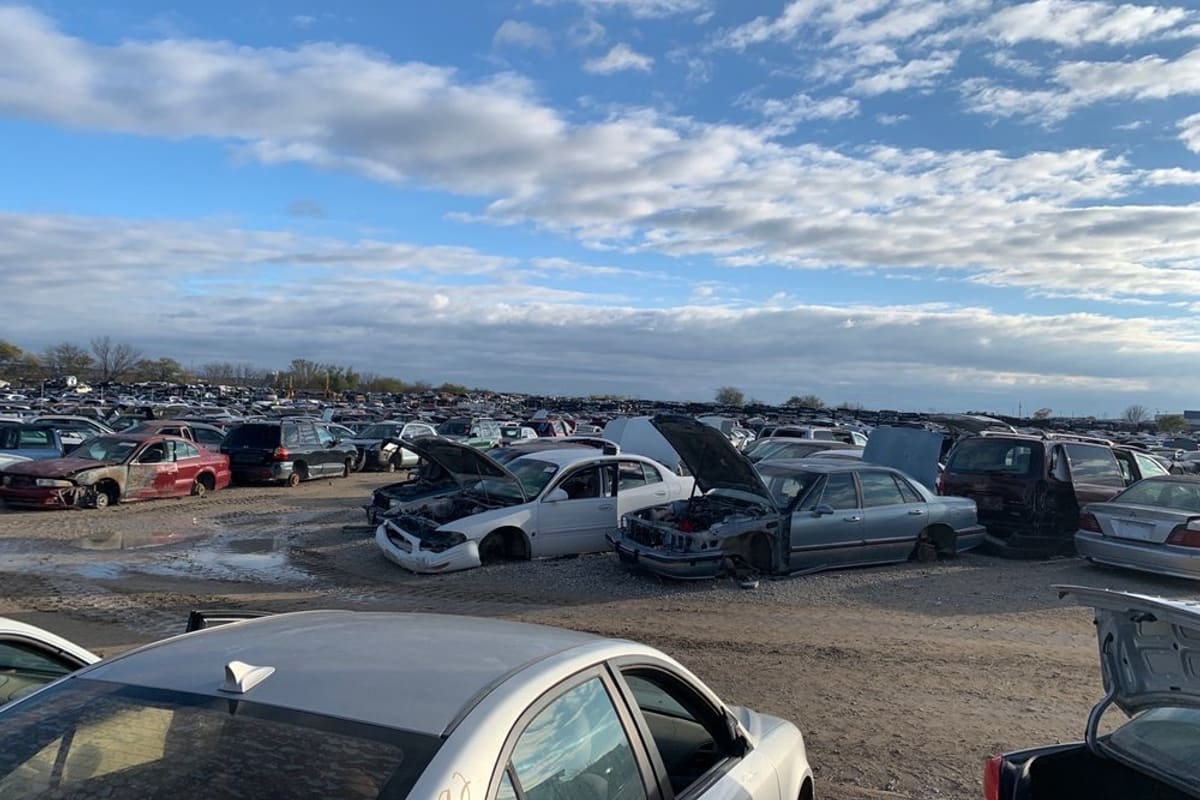 Winn's Allstate Auto Parts: Wide view of a large salvage yard with rows of wrecked cars on dirt under a partly cloudy sky
