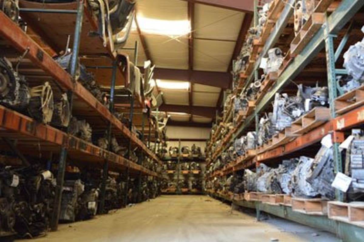 Martin's Auto Salvage: Warehouse aisle lined with tall shelves holding stored engines and transmissions under a steel-beam roof