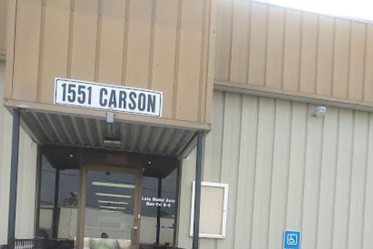 Fenix Parts Fort Worth: Front entrance of a tan metal building with a covered door, concrete steps, railings and a street number sign above