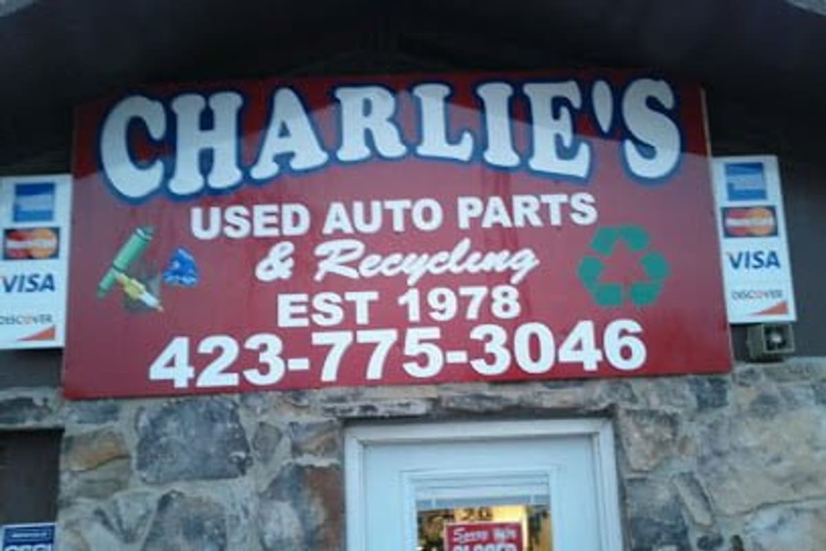 Charlies Used Auto Parts: Red storefront sign reading used auto parts and recycling, established 1978, above a stone wall and white door