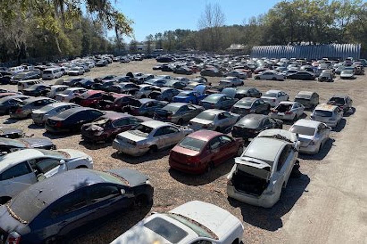 Big Sun Auto Salvage: Elevated view of a large dirt lot filled with rows of salvage cars under trees on a sunny day
