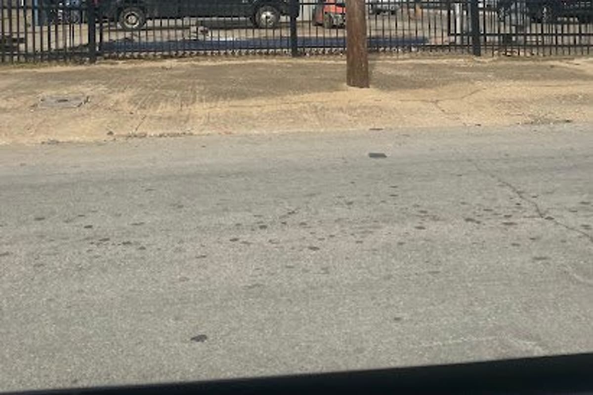 Northside Salvage & Scrap Metals: Metal building with a We Buy Scrap Metal sign behind a black iron fence, with a pickup truck and forklift in the lot