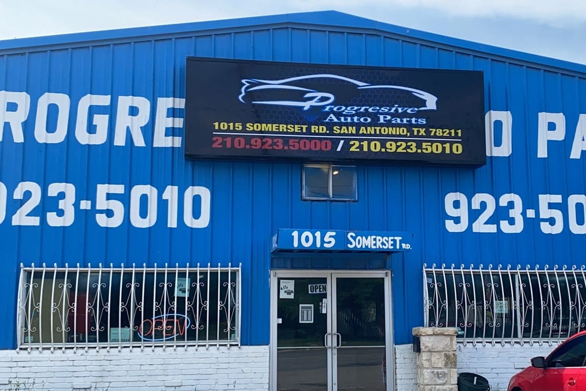 Progressive Ventures Holding: Blue metal building with a large lit sign, barred windows, glass entrance doors and a red car parked at the right