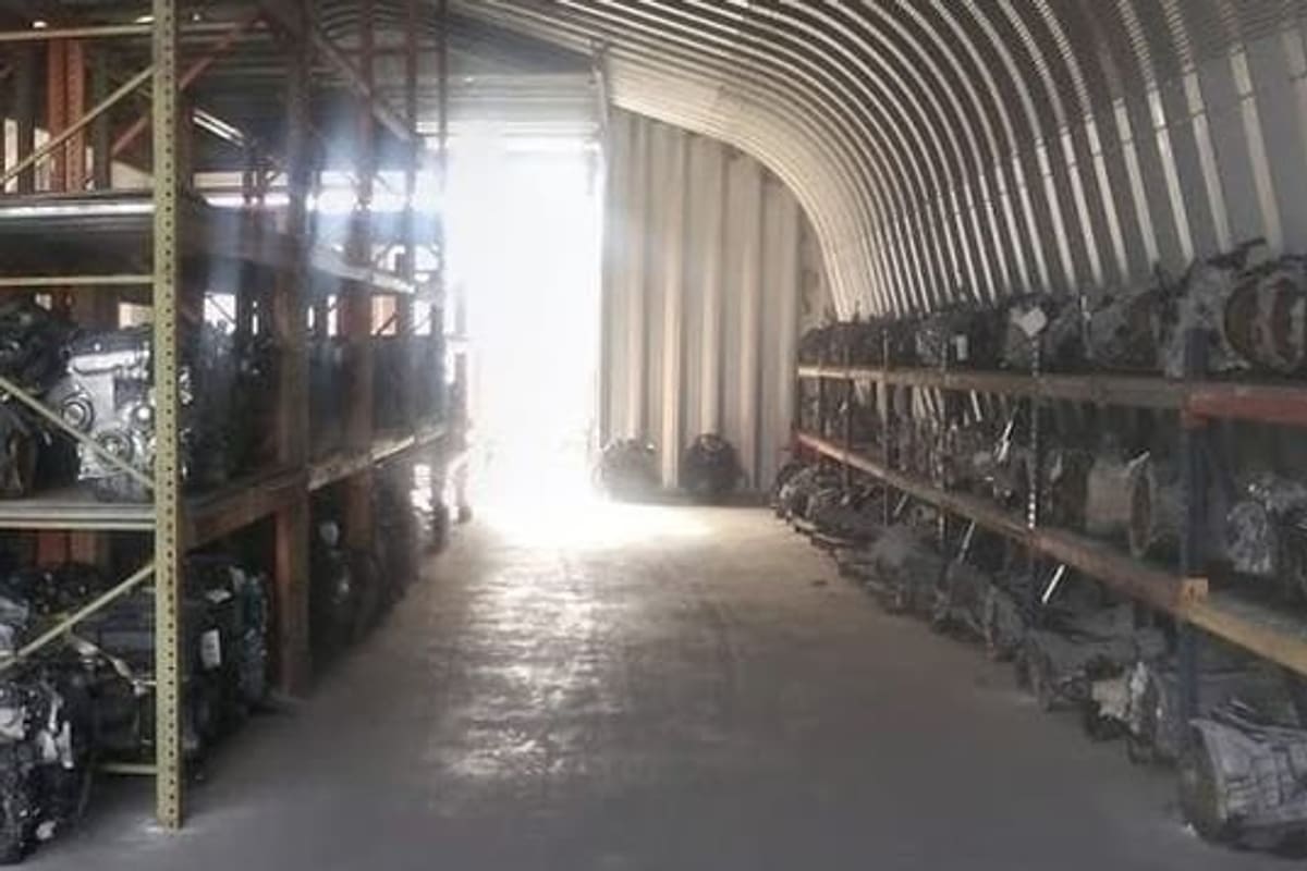 Eco Green Auto Parts: Inside a long arched metal storage building with shelving racks full of engines and transmissions along both sides