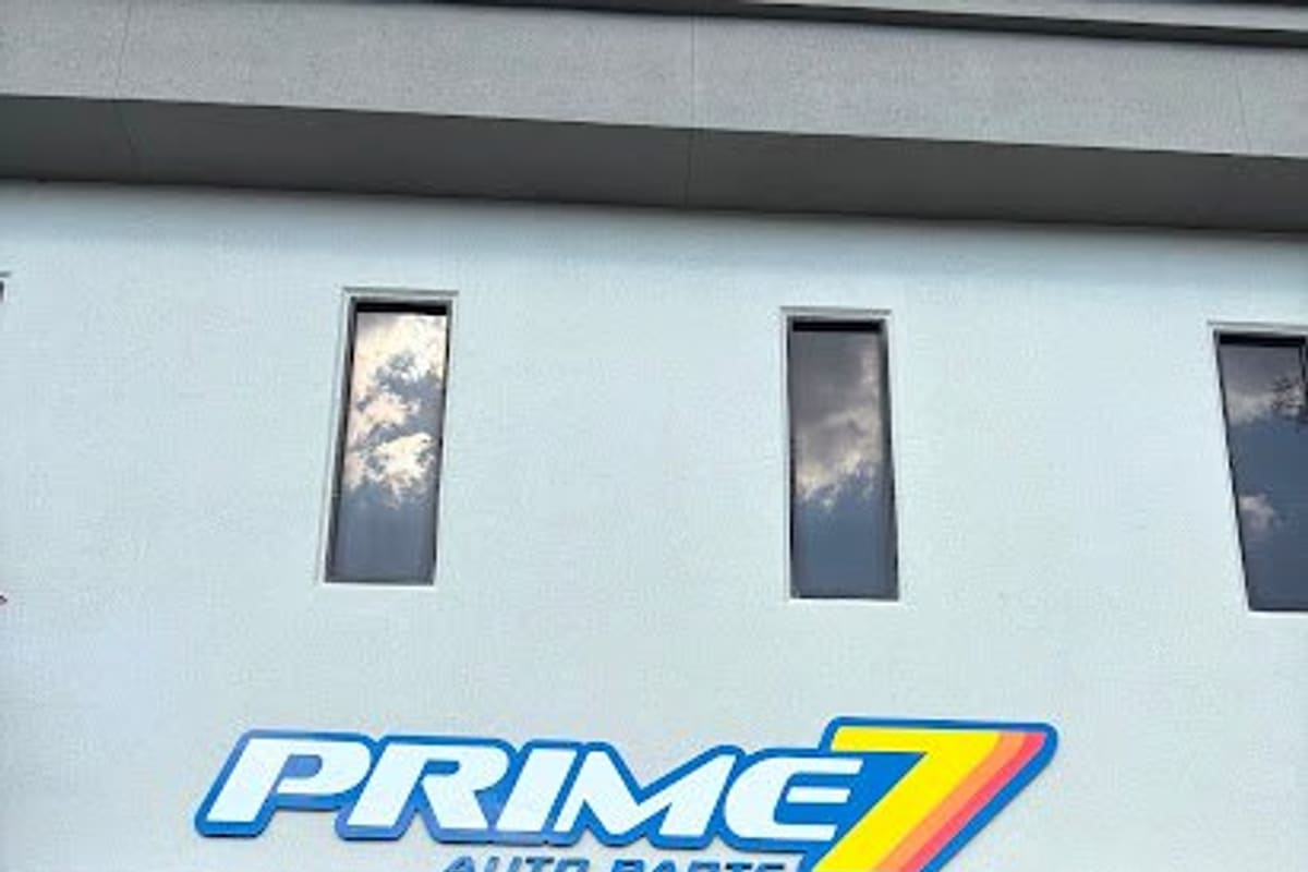 Prime 7 Auto Parts: Two-story stucco building with a large sign above glass entrance doors, street number 10551, and a sidewalk with grass