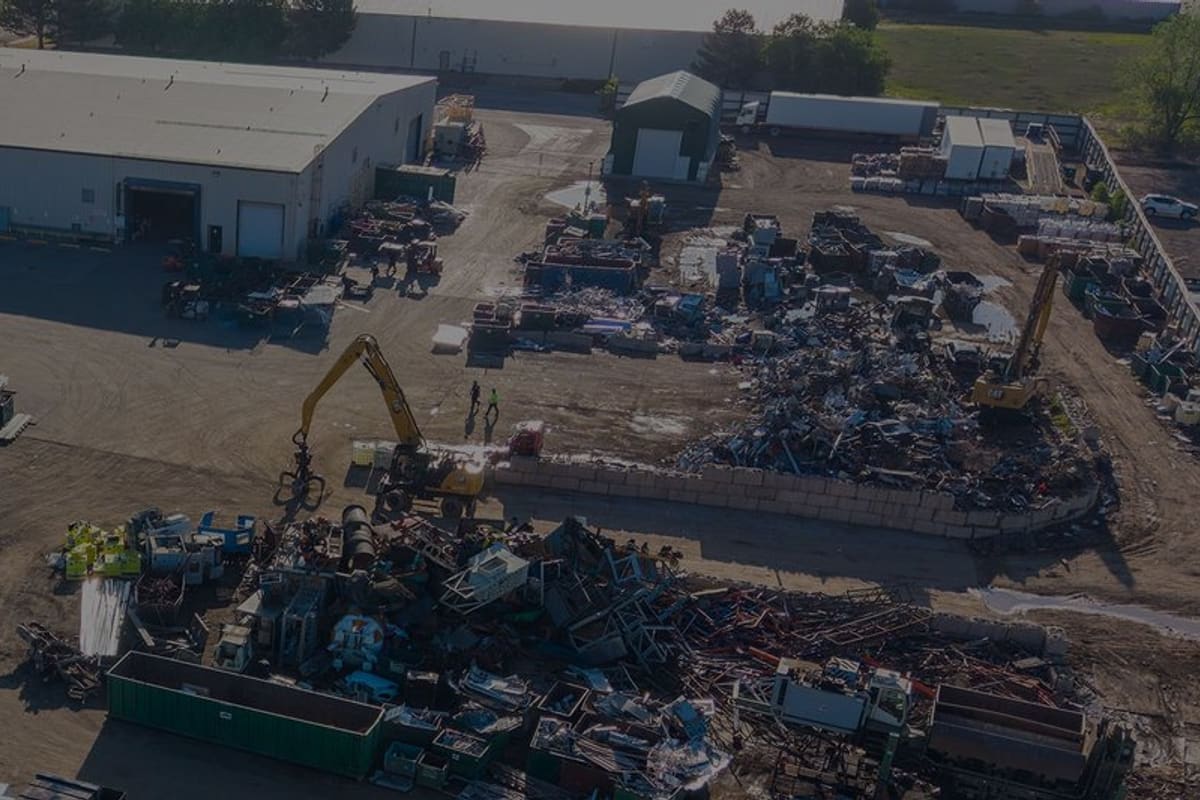 Colorado Iron & Metal: Aerial view of a scrap metal yard with a warehouse, scrap piles, an excavator, and rows of containers and trailers
