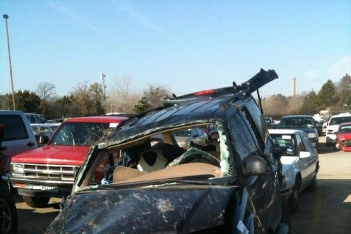 Eagle Truck & Auto Parts LC: Wrecked black SUV with a crushed front end in a lot filled with rows of parked vehicles on a sunny day