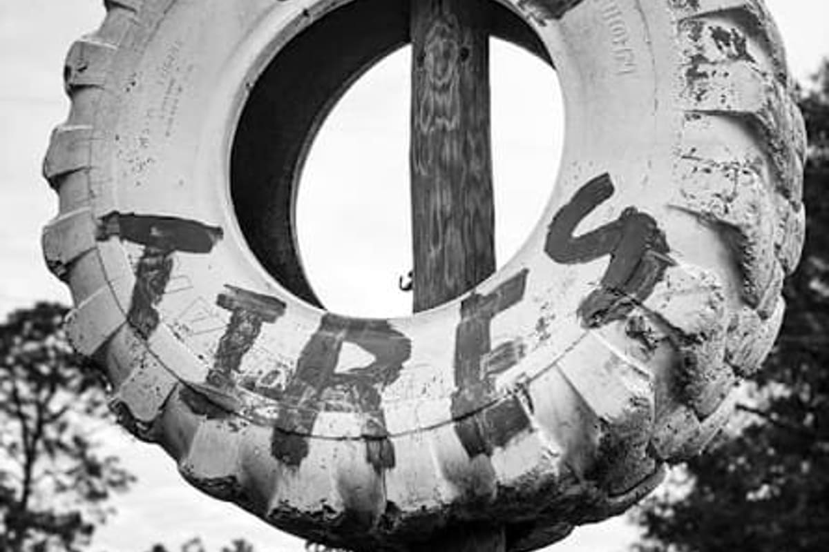 R & R Auto Salvage: Weathered roadside sign made from a large white tire painted with the words used tires, mounted on a wooden post