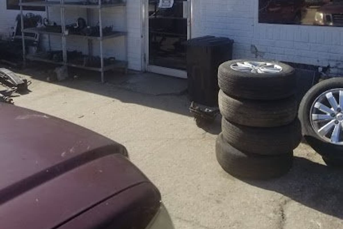 A To Z Auto Parts Two: White brick office building with a glass door, an OFFICE sign, a parts shelf and stacked tires out front