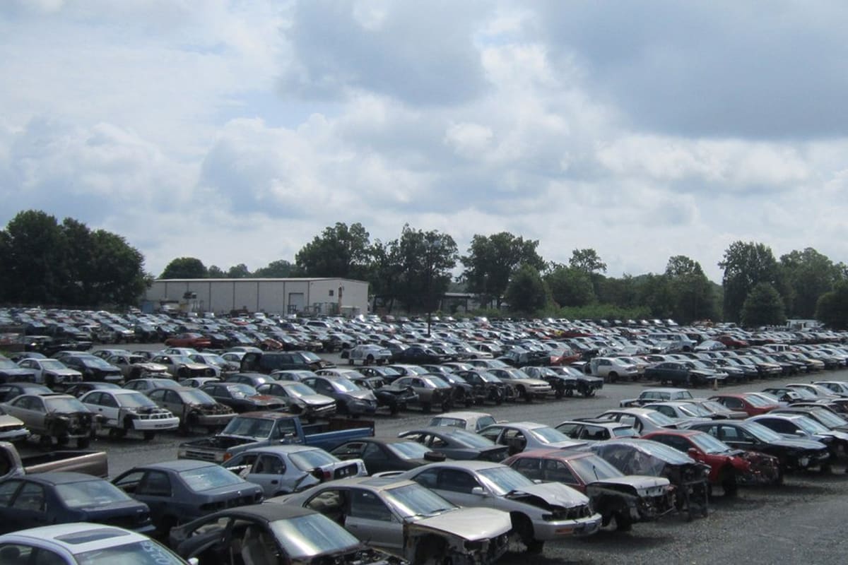 S&R Auto & Truck Salvage: Wide view of a salvage yard with rows of wrecked cars parked on gravel under a cloudy sky