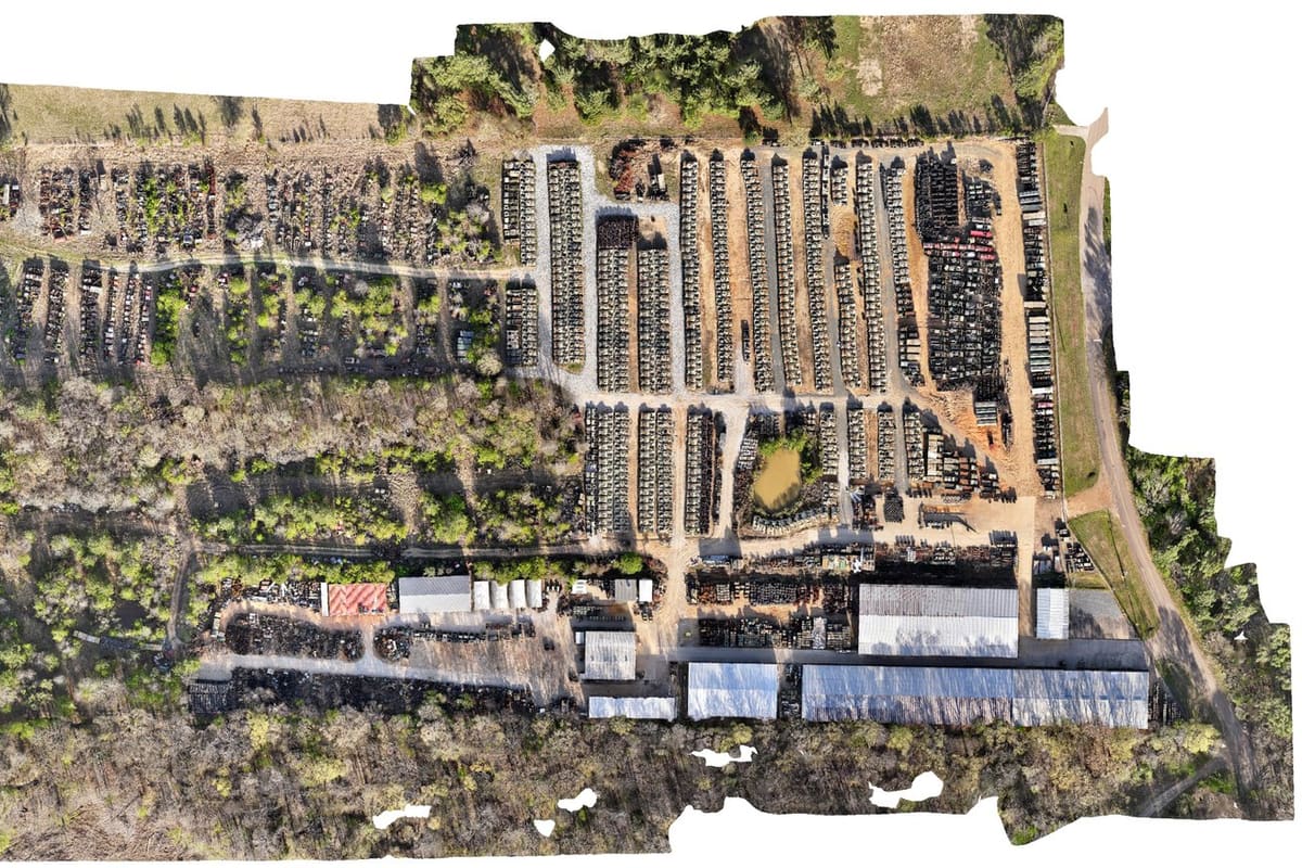 Red River Parts & Equipment: Aerial view of a large salvage yard with long rows of vehicles, storage sheds and ponds surrounded by woods