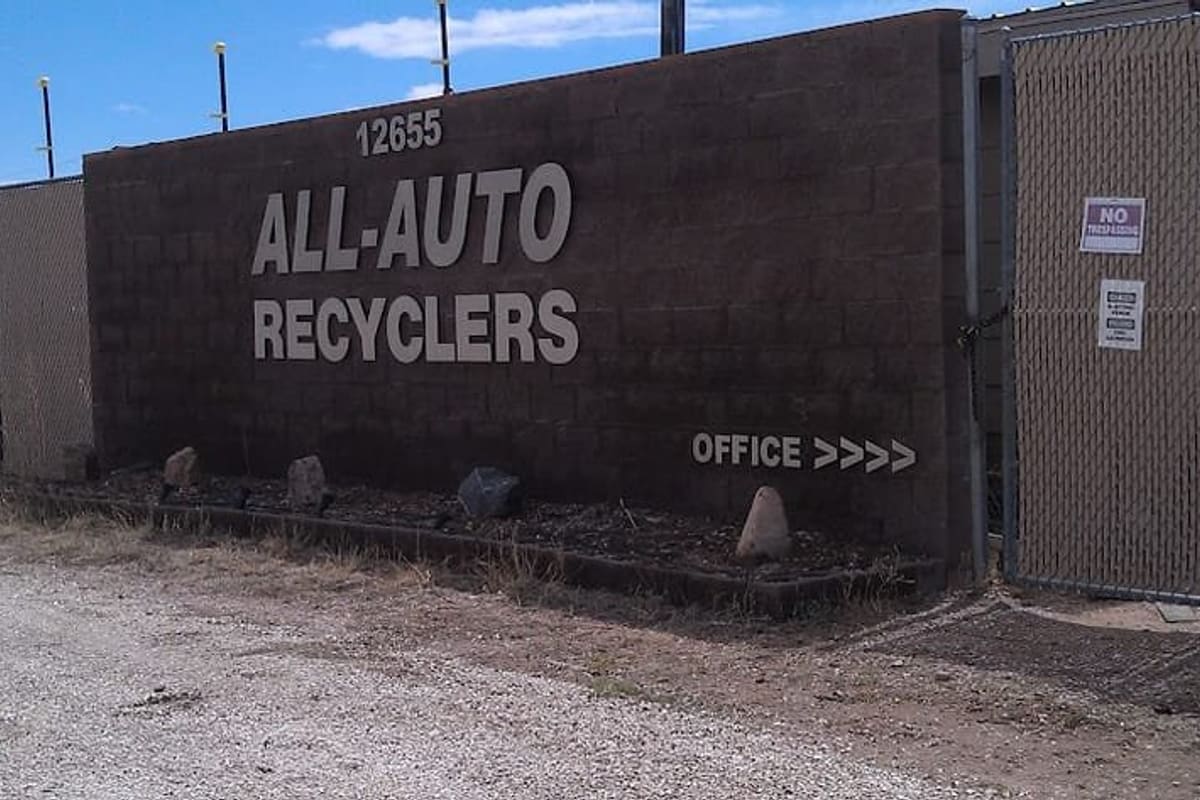 All Auto Recyclers: Brown block wall with large lettering reading All-Auto Recyclers, street number 12655 and an office arrow beside a chain-link gate