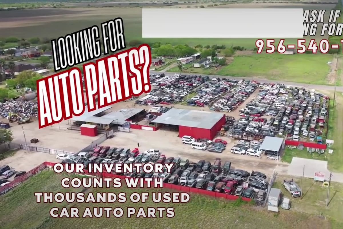 Pablo's Scrap Metal & Used Auto Parts: Aerial view of a large salvage yard with rows of used cars, a red metal building and a road alongside