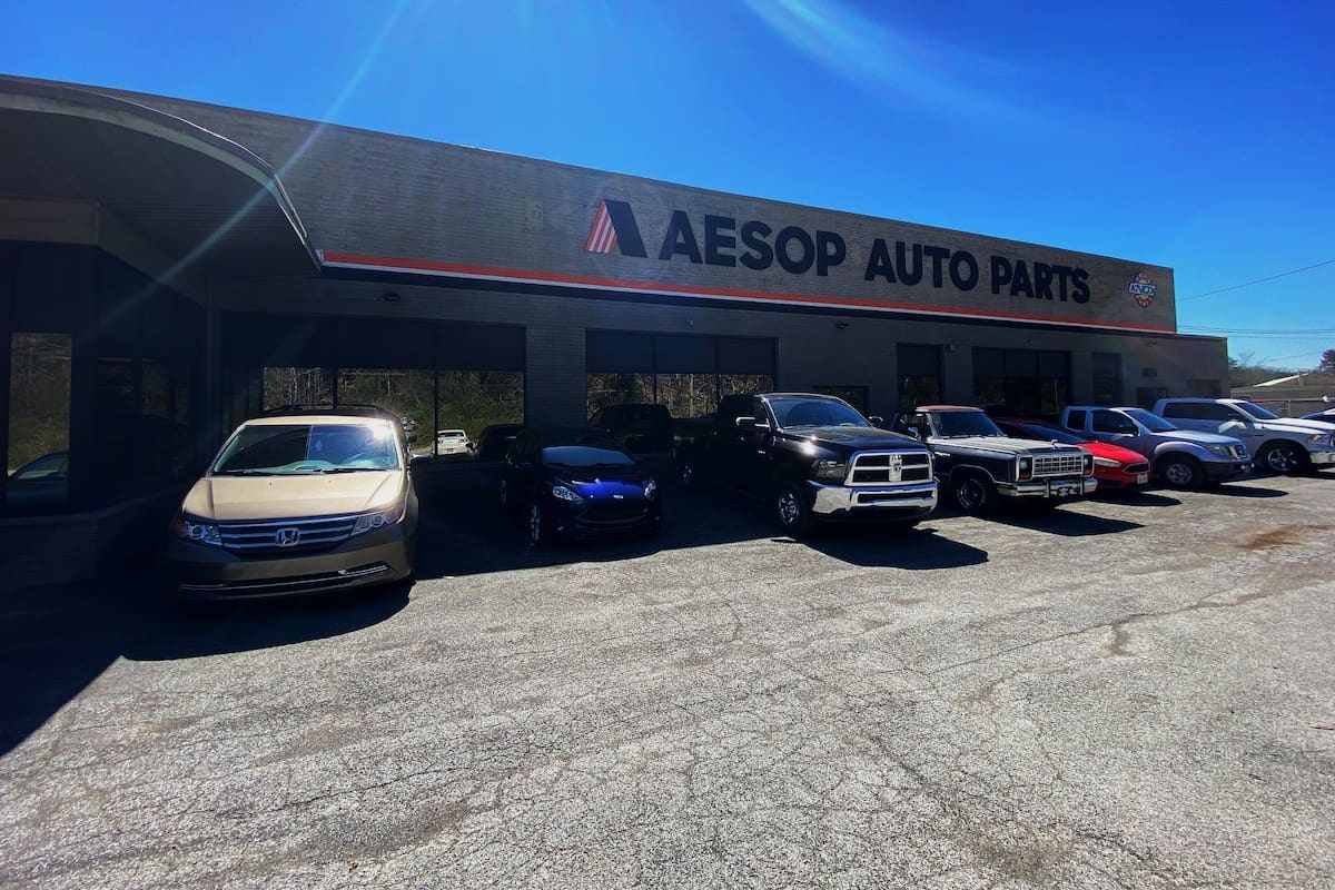 Aesop Auto Parts: Brick auto parts store with a large sign above the front and several cars and trucks parked on the paved lot