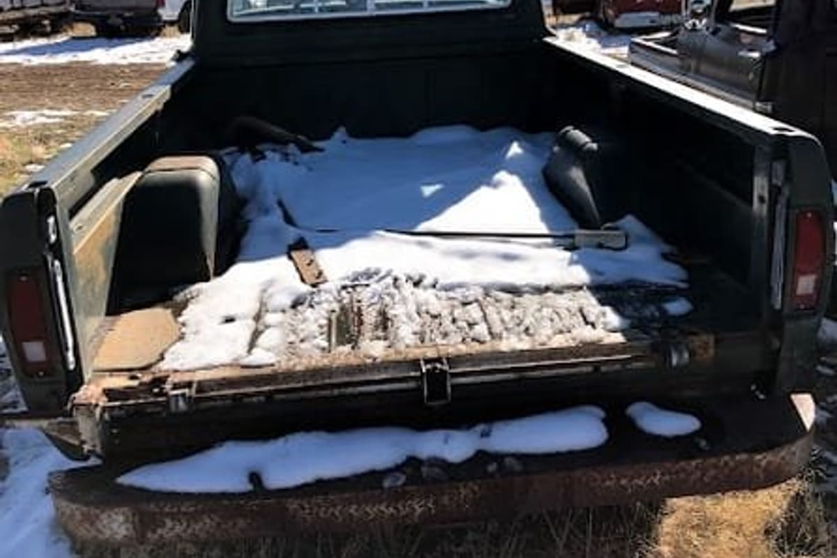 Erie Auto Salvage: Pickup truck bed dusted with snow in a salvage yard with other vehicles parked in the background