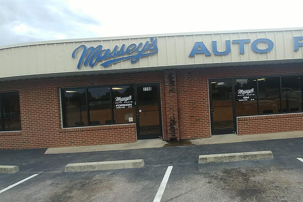 U-Pull-It: Brick storefront with a long blue auto parts sign above two glass entrance doors and a parking lot in front