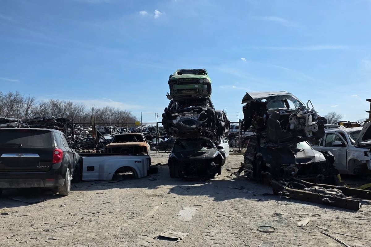 Affiliated Auto Parts & Winn's Used Cars: Wide daytime view of a salvage yard with stacked wrecked cars and rows of vehicles on a dirt lot under a blue sky
