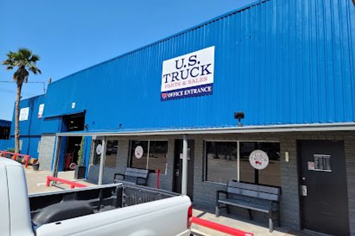 Truck Salvage: Blue metal building with a large truck parts and sales sign reading office entrance above a covered walkway with benches