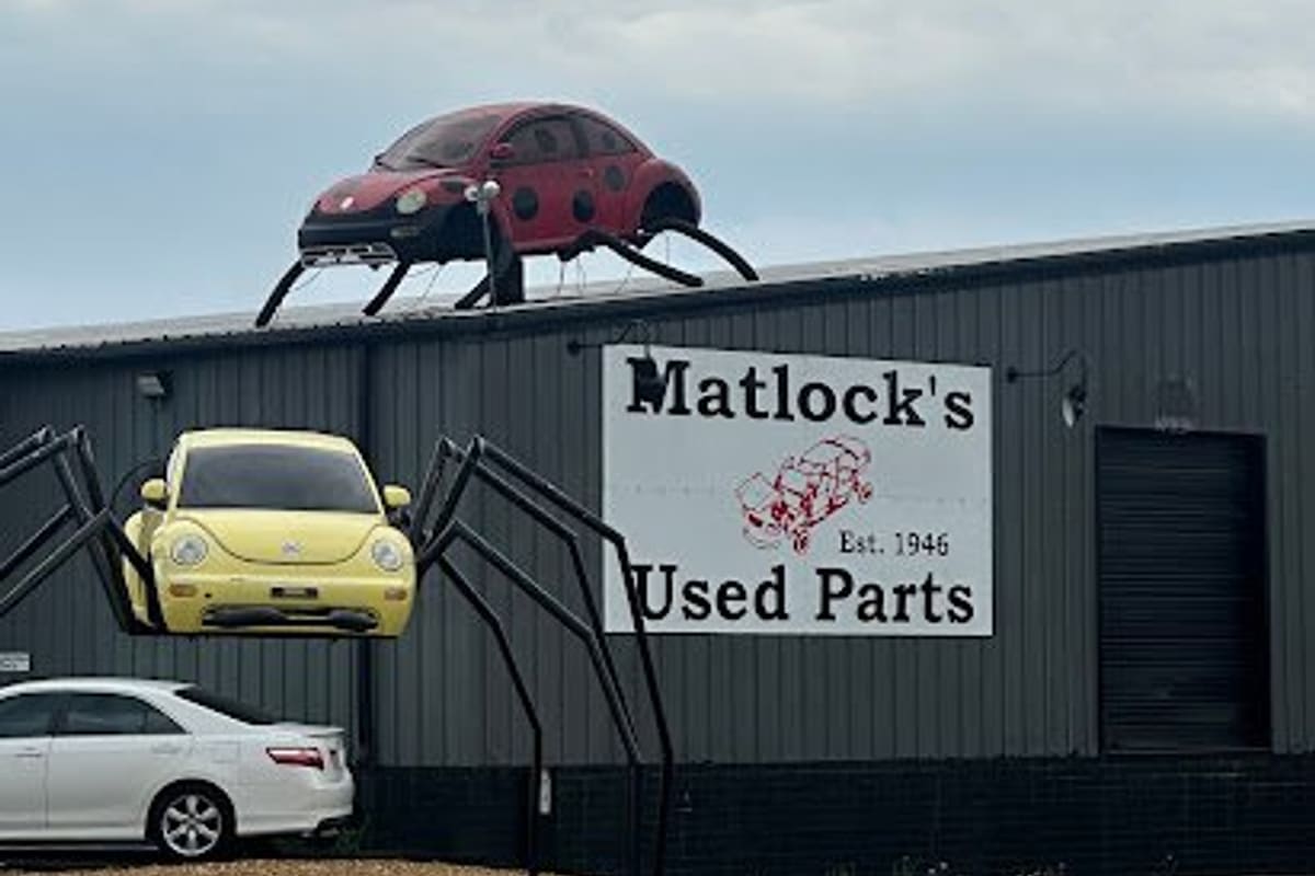 Matlock's Used Car and Parts - Catawba: Metal warehouse building with a large used parts sign and car sculptures with spider legs on the roof and wall