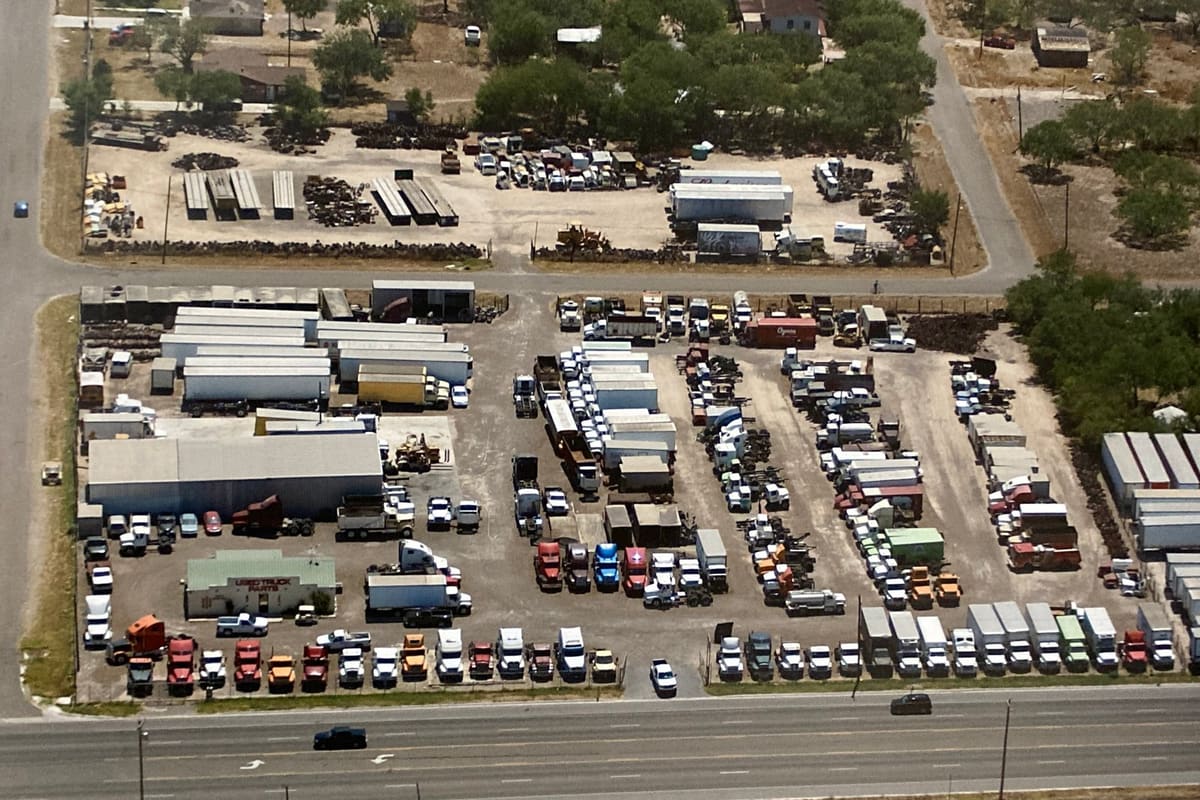 Gonzalez Truck & Equipment: Aerial view of a truck salvage yard with rows of trucks, trailers and parts beside a highway