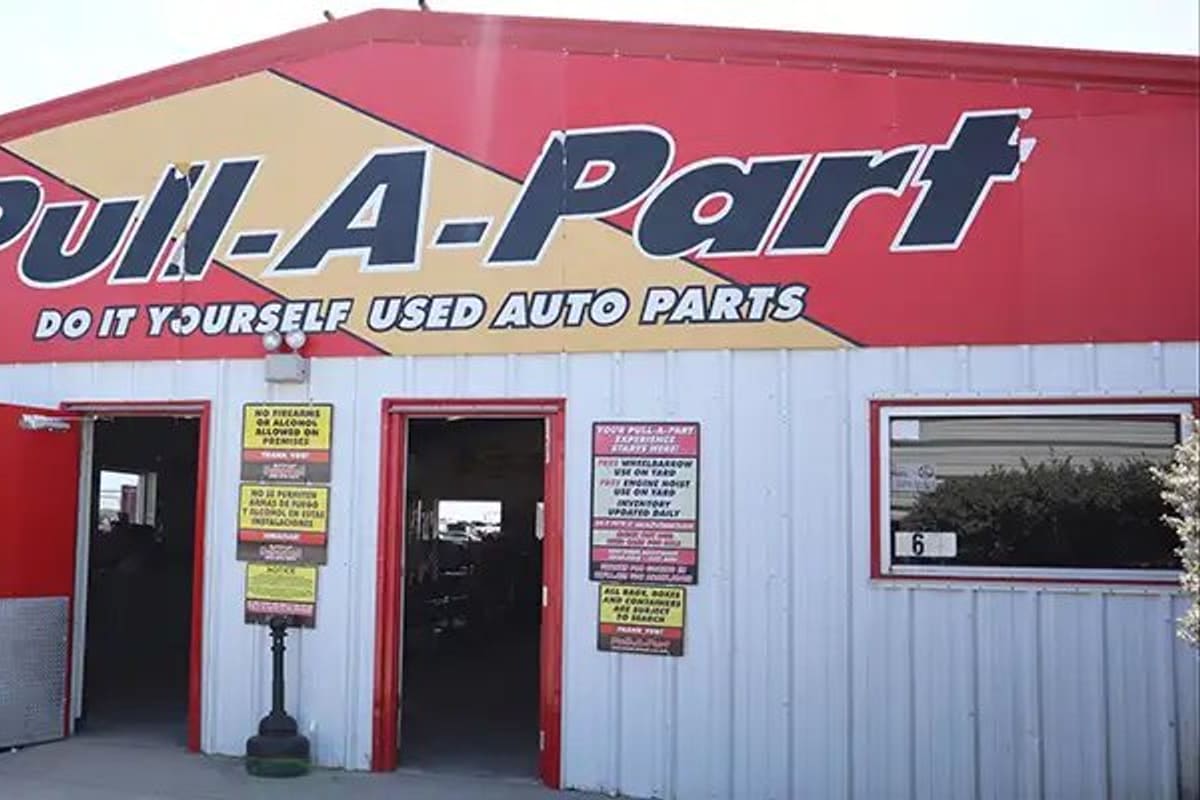 Pull-A-Part Corpus Christi: Red and white metal building with large painted sign over open doorways and posted rules signs