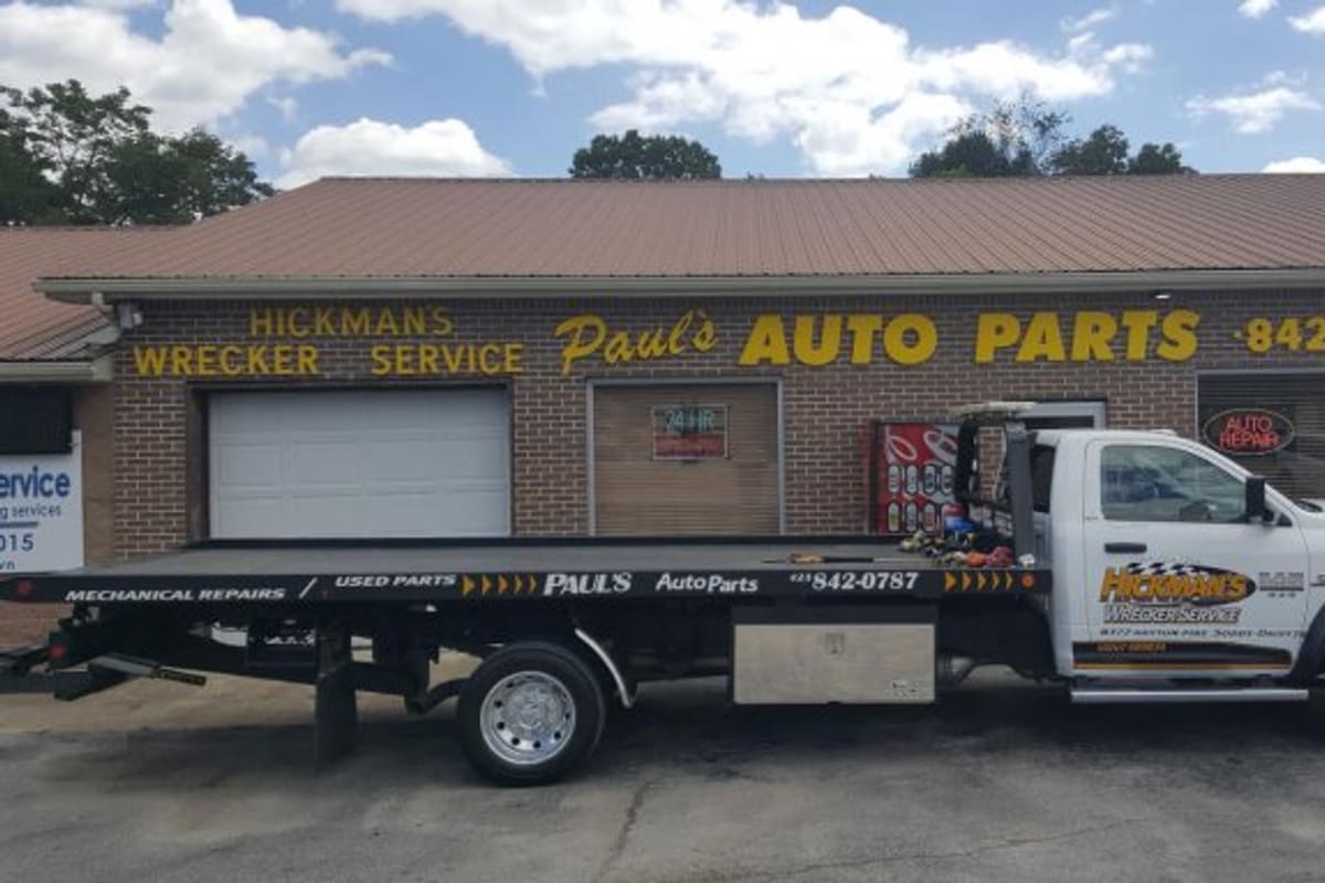 Paul's New & Used Auto Parts: Brick auto parts building with a yellow painted sign above the bays and a flatbed tow truck parked in front