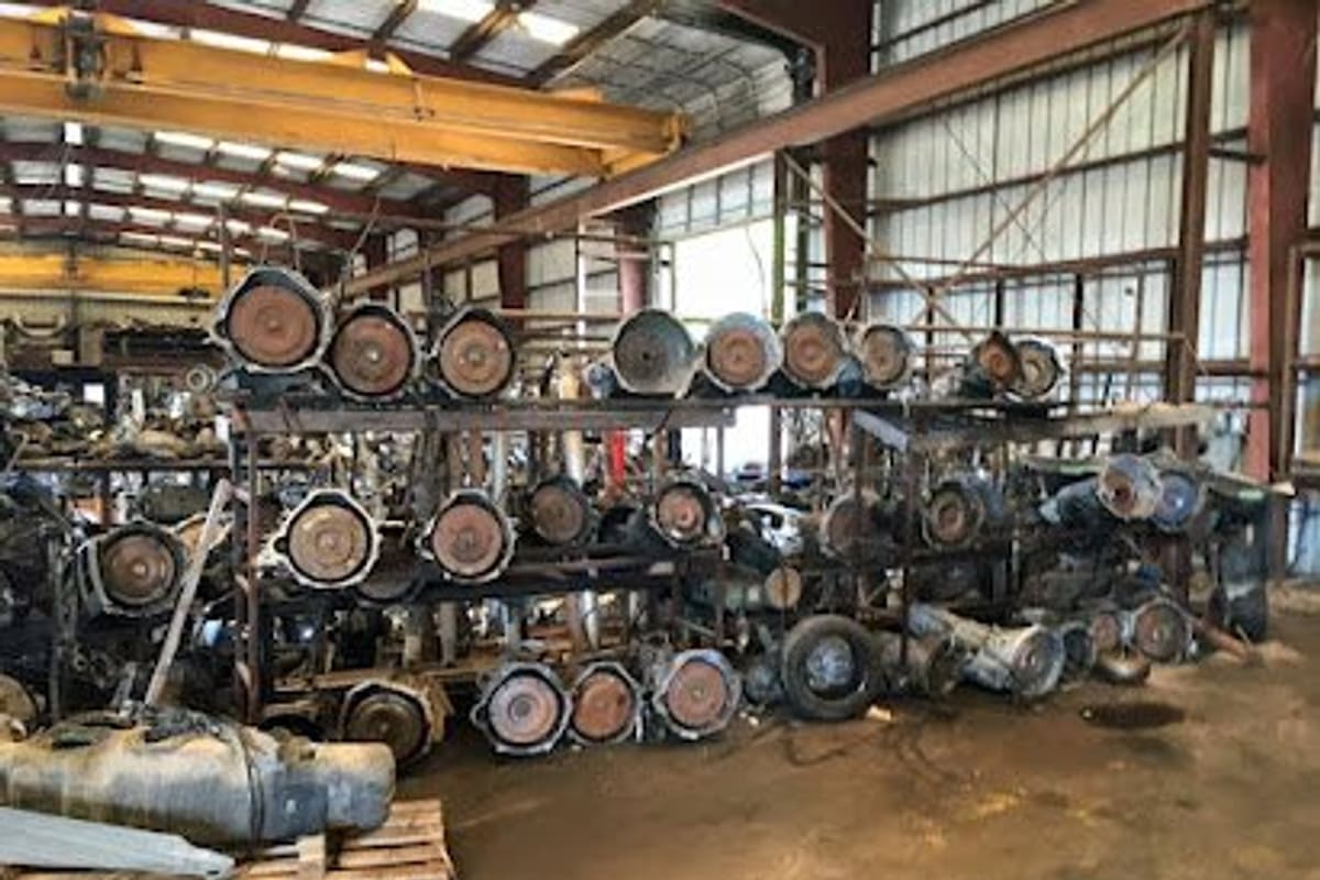 C & D Quality Auto Parts: Inside a large metal warehouse with racks of salvaged truck transmissions and drivetrain parts under an overhead crane