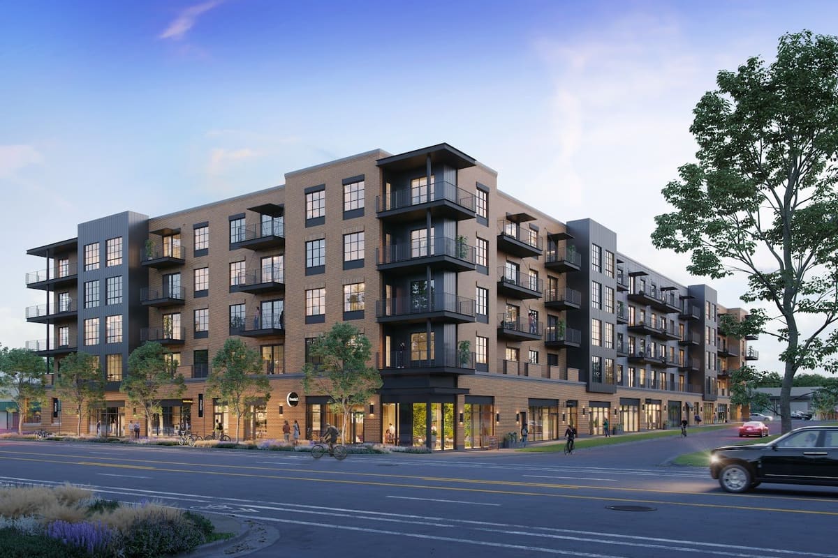 Congress Lofts: Five-story brick and dark metal apartment building with ground-floor storefronts along a street at dusk